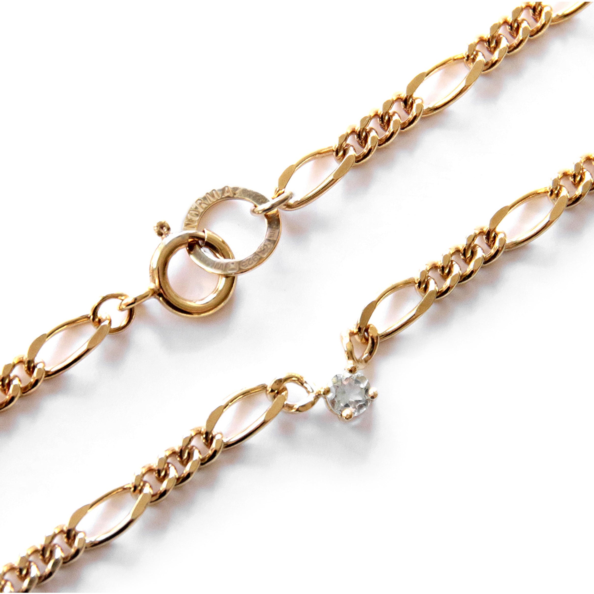 Gold chain necklace with a small aquamarine pendant on a white background