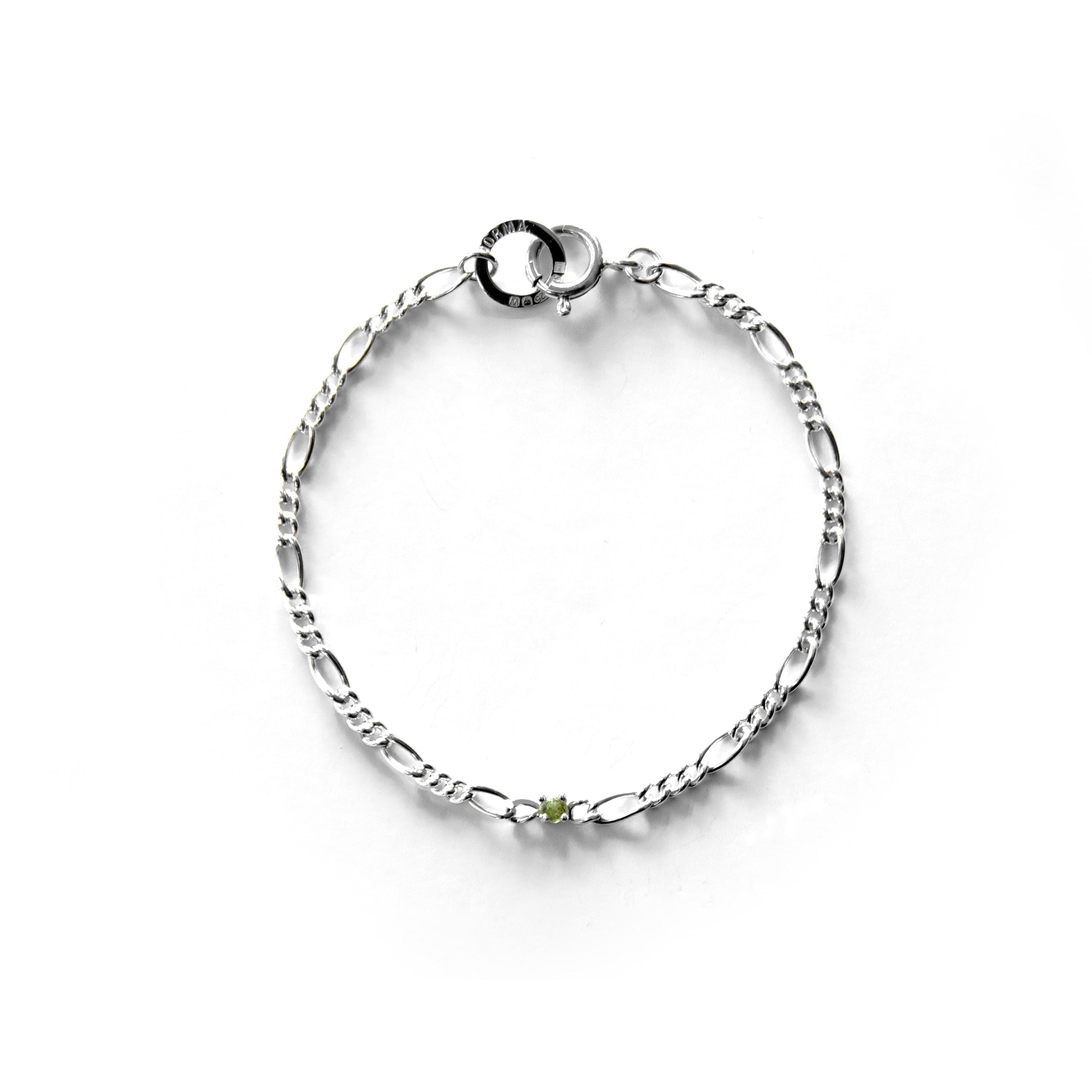 Silver bracelet with a small peridot round charm on a white background